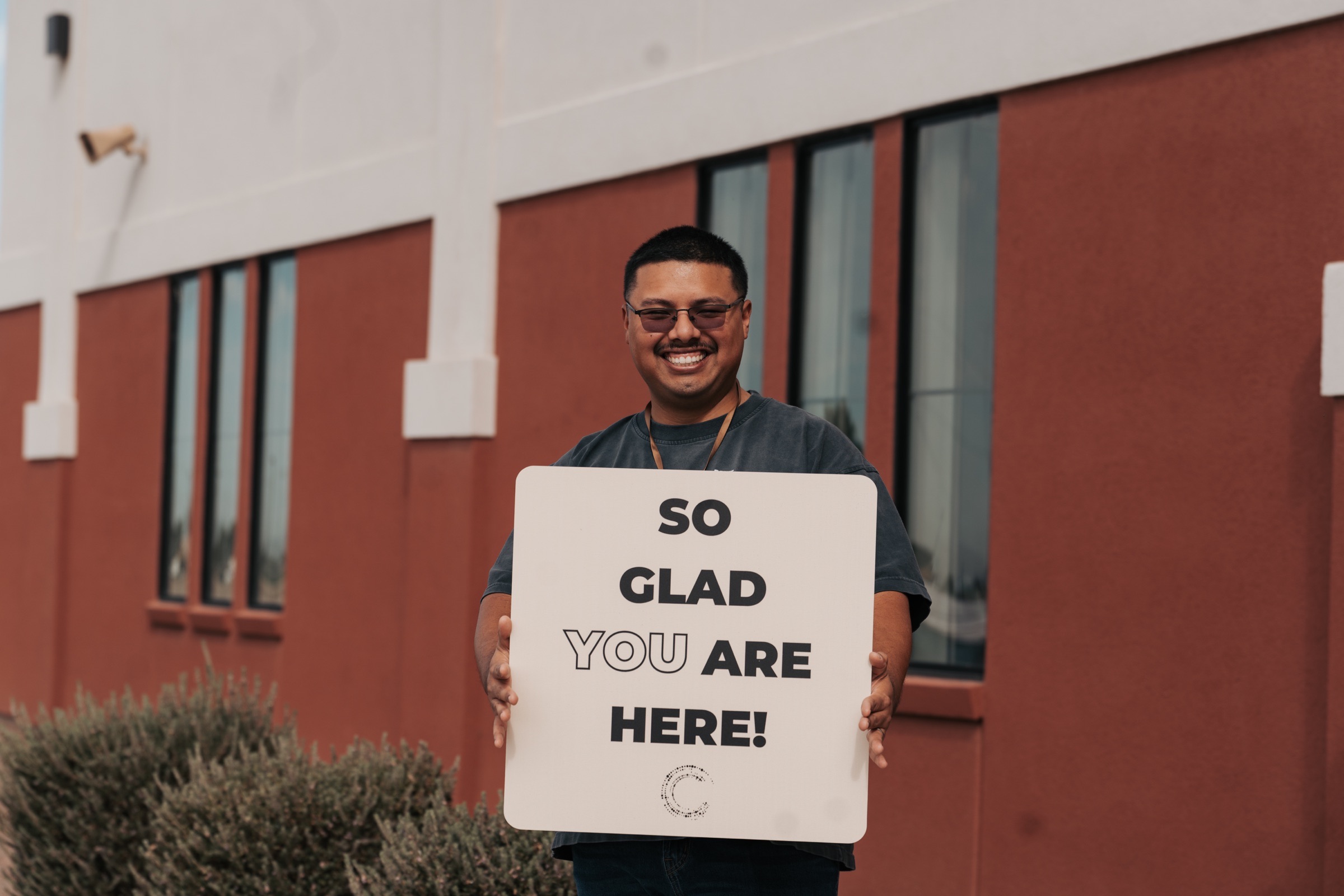 An Orbit Church volunteer holding a sign that welcomes guests